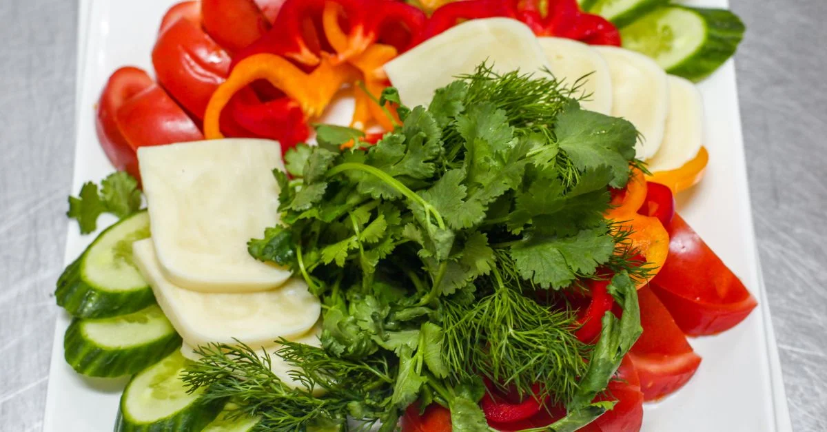 Assortiment coloré de légumes frais et d'herbes sur un plat pour un repas sain.