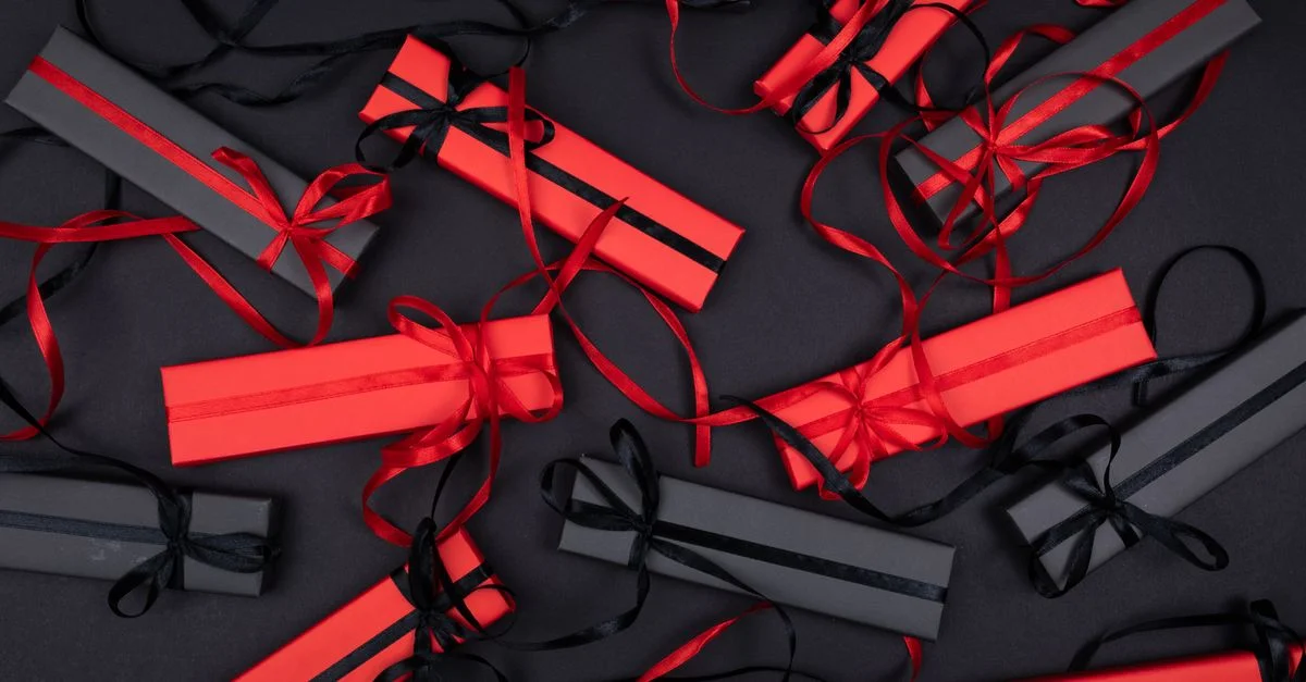 Vue de dessus de boîtes cadeaux rouges et noires élégamment disposées avec des rubans, créant un look festif et sophistiqué.