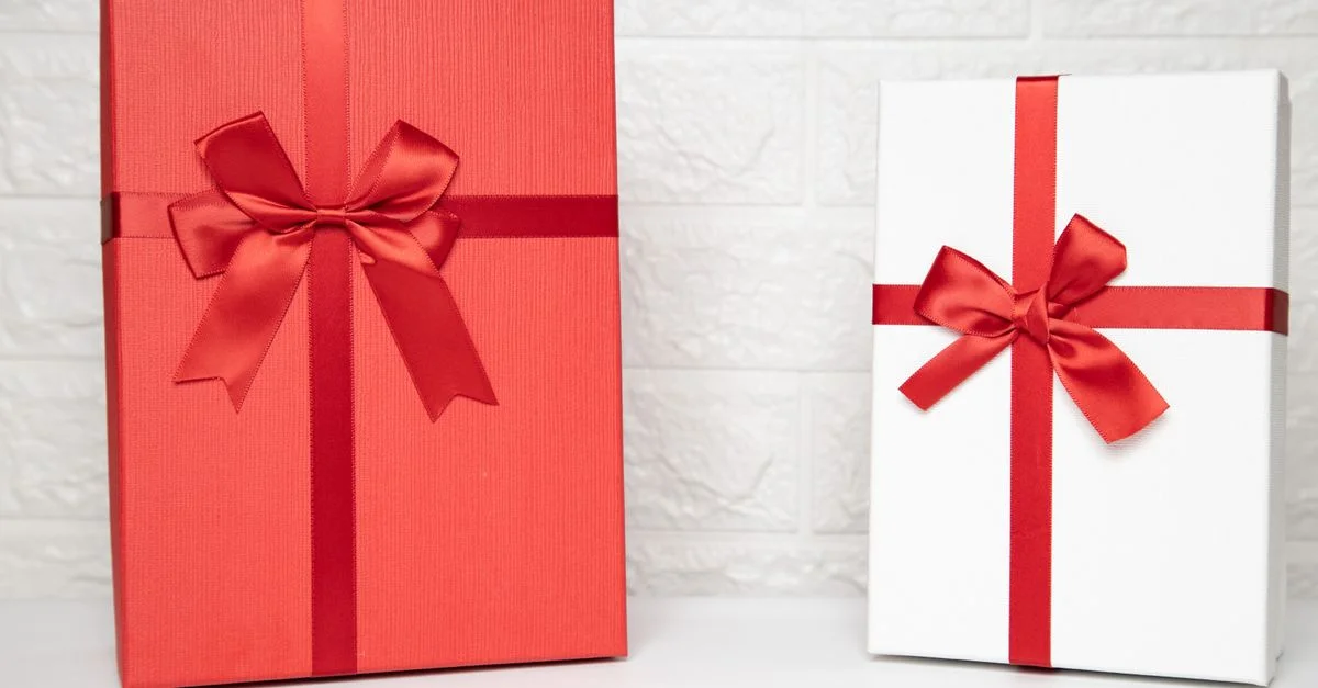 Deux boîtes cadeaux élégantes avec des rubans rouges sur un fond intérieur blanc, parfaites pour les célébrations.