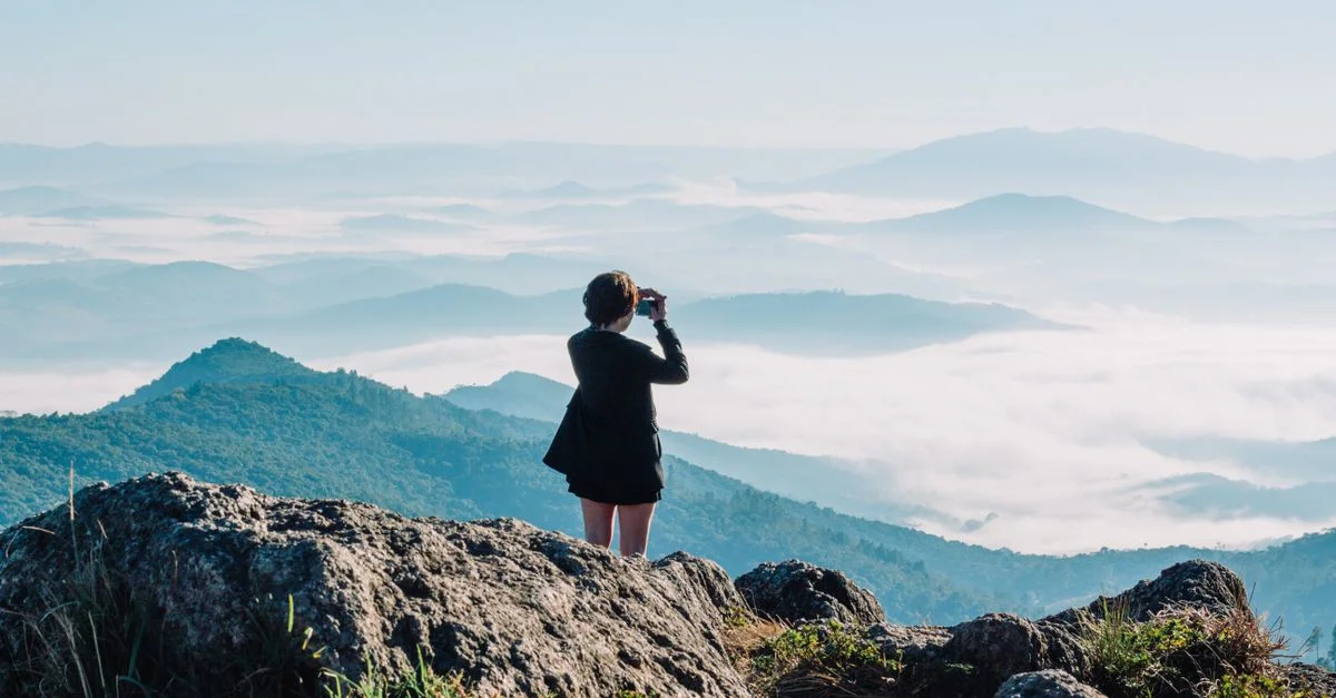Une femme apprécie une vue panoramique sur les montagnes avec des jumelles, capturant l'essence aventureuse de la nature.