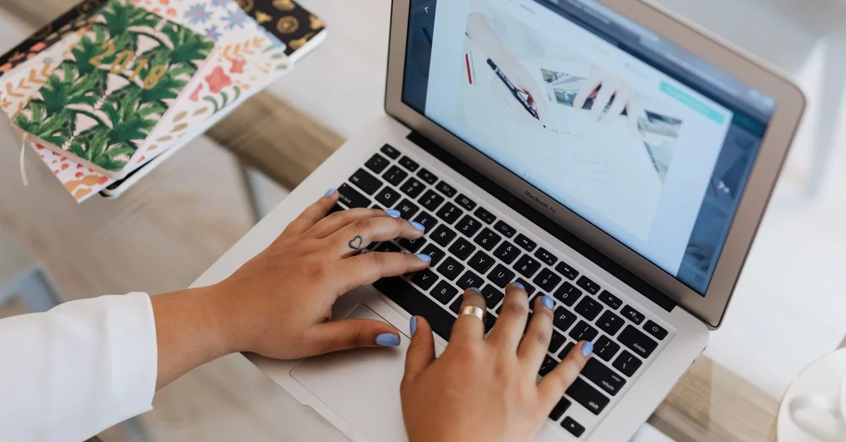 Gros plan des mains tapant sur un ordinateur portable sur un bureau de bureau élégant avec des carnets.