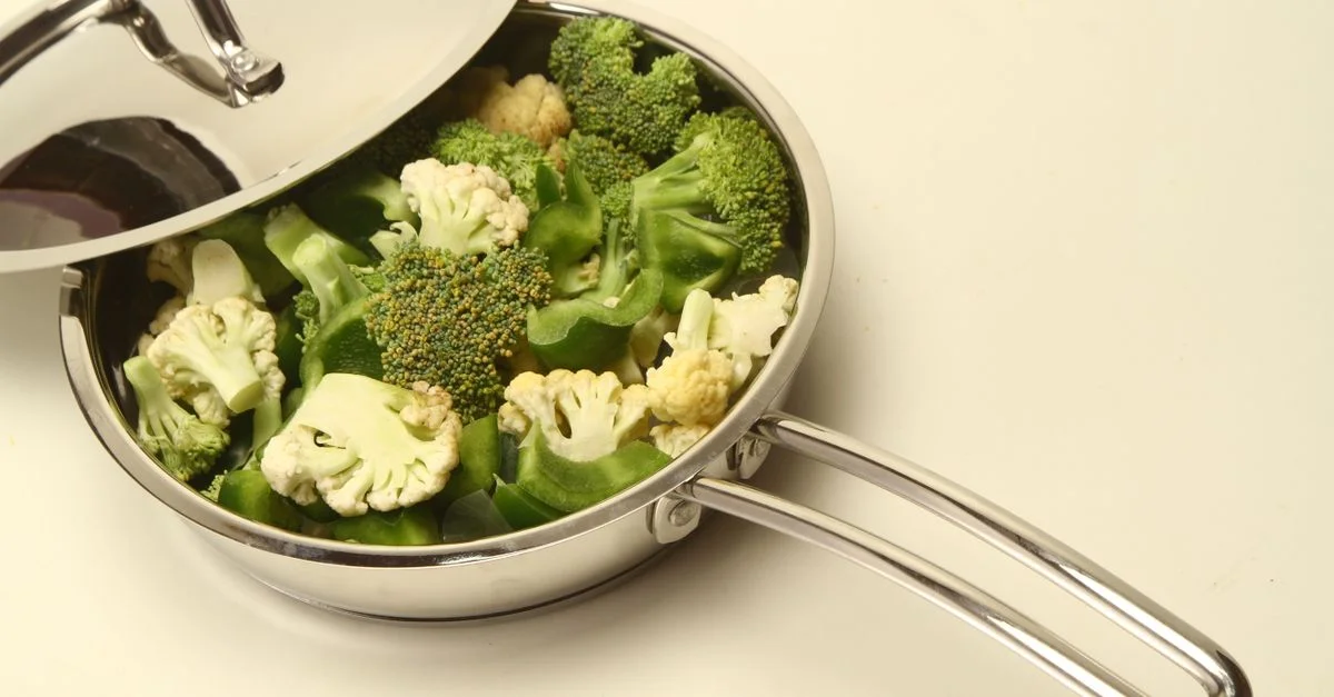 Vue en plongée de brocoli et de chou-fleur dans une poêle en acier inoxydable, parfaite pour une inspiration culinaire saine.